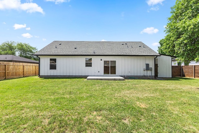 back of house with board and batten siding, a shingled roof, a fenced backyard, and a yard