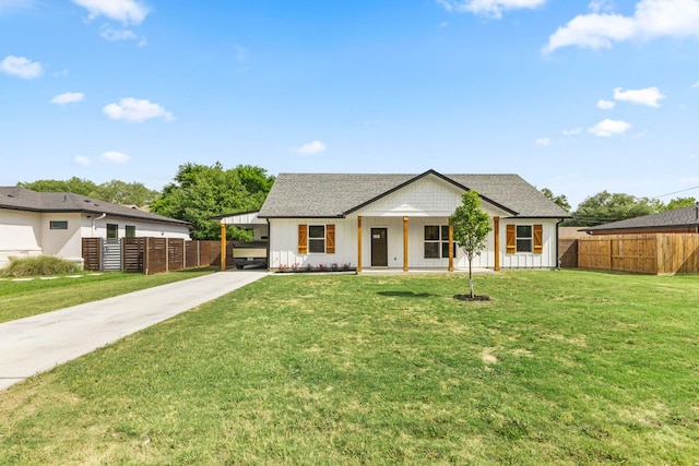 modern farmhouse style home with board and batten siding, a front lawn, concrete driveway, and fence