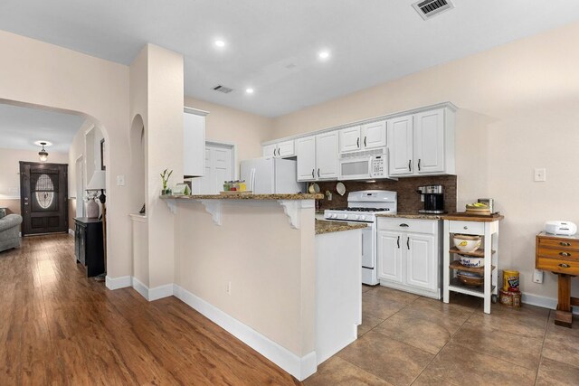 3325 Cantera Way, Round Rock, TX 78681 - kitchen featuring white appliances, arched walkways, a breakfast bar area, a peninsula, and white cabinets