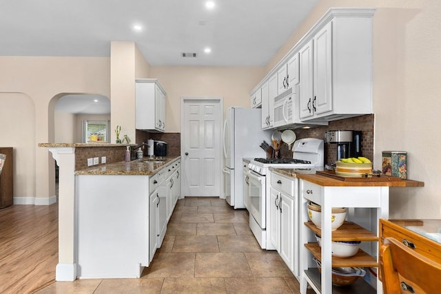 3325 Cantera Way, Round Rock, TX 78681 - kitchen with white appliances, backsplash, a sink, arched walkways, and dark stone countertops