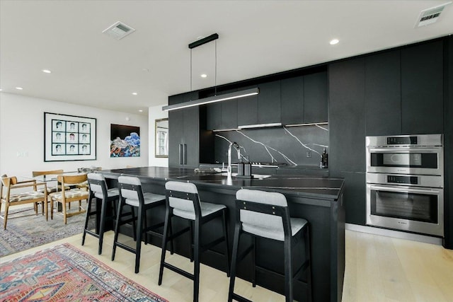 44 E Ave Unit 3906, Austin, TX 78701 - kitchen featuring double oven, modern cabinets, dark countertops, dark cabinets, and a breakfast bar area