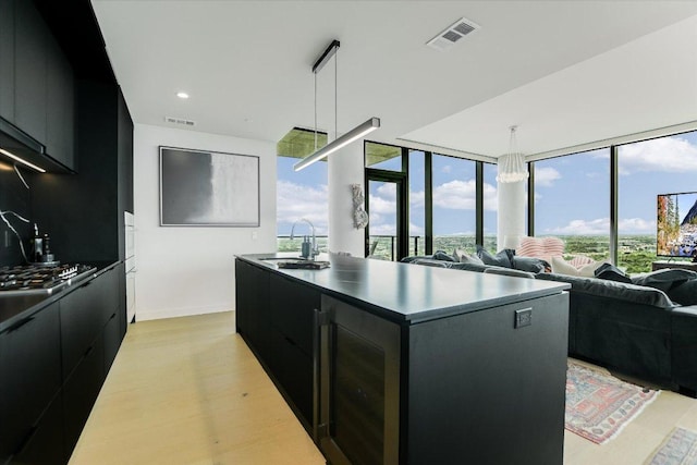 44 E Ave Unit 3906, Austin, TX 78701 - kitchen featuring dark cabinets, modern cabinets, stainless steel gas stovetop, an island with sink, and decorative light fixtures