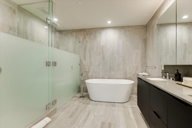 44 E Ave Unit 3906, Austin, TX 78701 - full bathroom with tile walls, a stall shower, a freestanding bath, double vanity, and recessed lighting