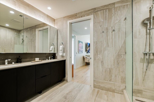 44 E Ave Unit 3906, Austin, TX 78701 - full bath featuring a tile shower, double vanity, recessed lighting, tile walls, and wood finished floors