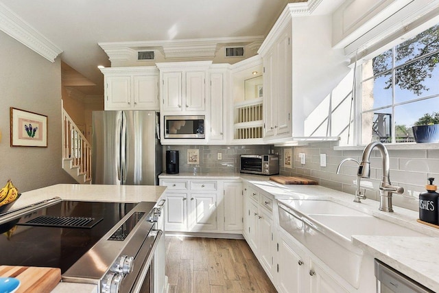 203 Saddle Blanket Dr, Dripping Springs, TX 78620 - kitchen with stainless steel appliances, crown molding, light wood-style flooring, decorative backsplash, and white cabinets