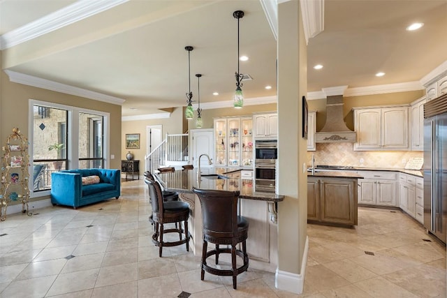 4616 High Gate Dr, Austin, TX 78730 - kitchen with wall chimney exhaust hood, an island with sink, a breakfast bar area, decorative backsplash, and crown molding