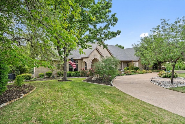 4616 High Gate Dr, Austin, TX 78730 - view of front of home featuring a front yard, curved driveway, roof with shingles, and stone siding