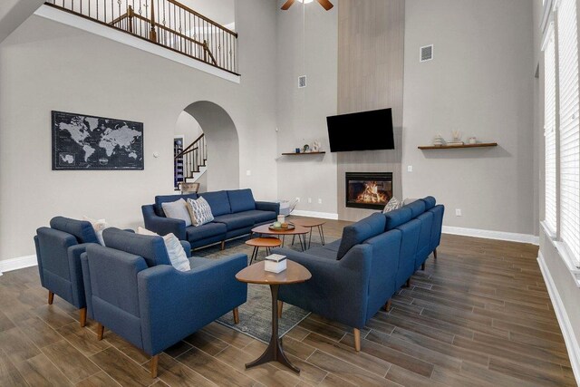 2601 Montebelluna Pl, Leander, TX 78641 - living room with a high ceiling, dark wood-style floors, ceiling fan, arched walkways, and a tile fireplace