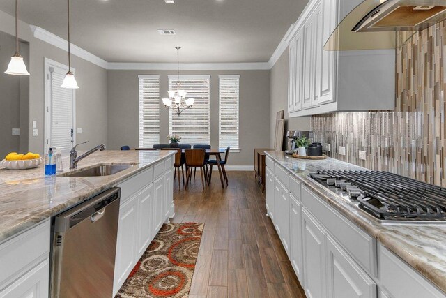 2601 Montebelluna Pl, Leander, TX 78641 - kitchen featuring appliances with stainless steel finishes, range hood, dark wood finished floors, backsplash, and white cabinetry