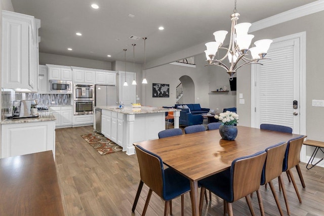 2601 Montebelluna Pl, Leander, TX 78641 - dining space featuring arched walkways, recessed lighting, light wood-type flooring, crown molding, and a chandelier