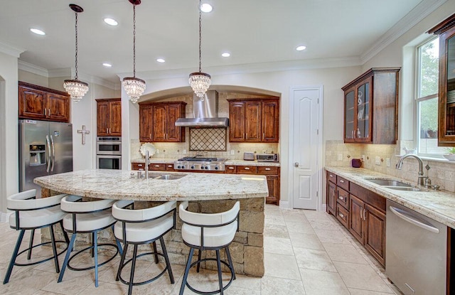 kitchen featuring wall chimney exhaust hood, a sink, an island with sink, and appliances with stainless steel finishes