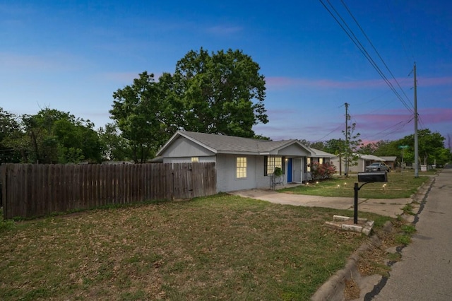 view of front of house with fence, driveway, and a yard