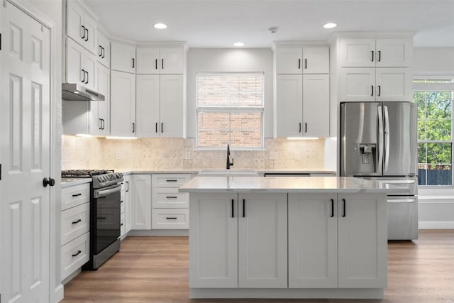 1006 Mesquite Hollow Pl, Round Rock, TX 78665 - kitchen with stainless steel appliances, a sink, a kitchen island, light wood finished floors, and white cabinetry