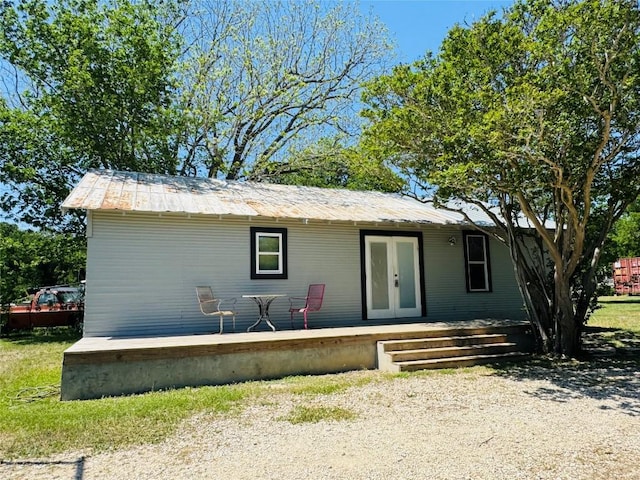 back of property with a standing seam roof, covered porch, french doors, and metal roof