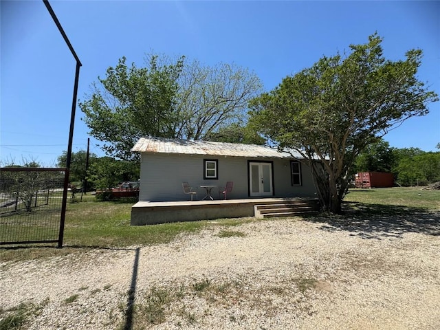 back of property with a lawn, metal roof, and french doors