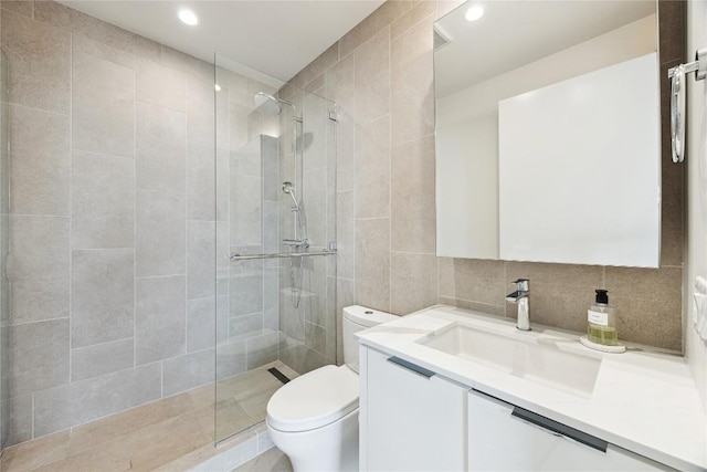 bathroom featuring recessed lighting, toilet, vanity, a walk in shower, and tile walls