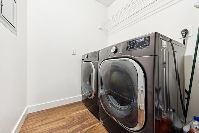laundry room with baseboards, wood finished floors, washer and clothes dryer, and laundry area
