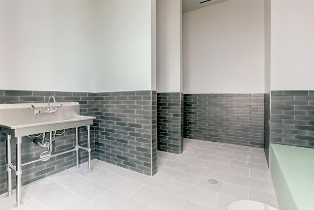 bathroom featuring tile walls, a wainscoted wall, a sink, and tile patterned floors