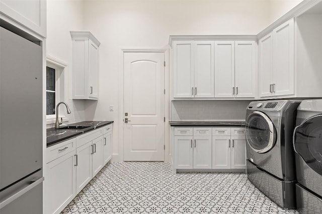 clothes washing area with cabinet space, washing machine and dryer, and a sink