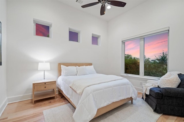 bedroom with visible vents, light wood finished floors, baseboards, and ceiling fan