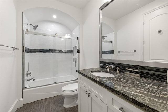 full bath featuring wood finished floors, bath / shower combo with glass door, toilet, and vanity
