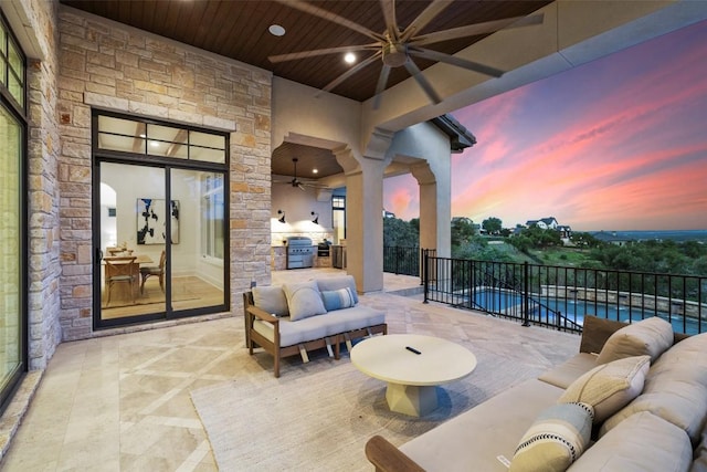 patio terrace at dusk featuring an outdoor living space, ceiling fan, a fenced in pool, and fence