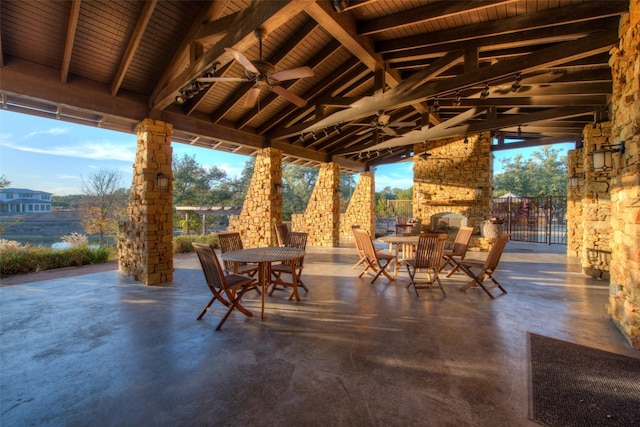 view of patio / terrace featuring outdoor dining area, an outdoor stone fireplace, and ceiling fan