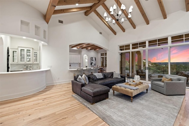 living area with visible vents, arched walkways, a notable chandelier, and high vaulted ceiling