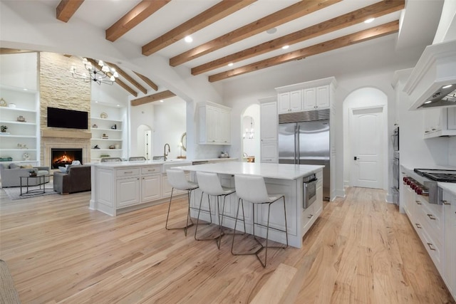 kitchen featuring a center island, arched walkways, appliances with stainless steel finishes, and a fireplace
