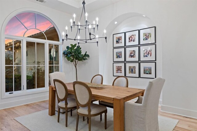 dining room with a chandelier, light wood-type flooring, visible vents, and baseboards