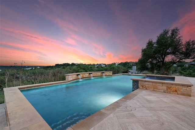 pool at dusk with an outdoor pool and an in ground hot tub