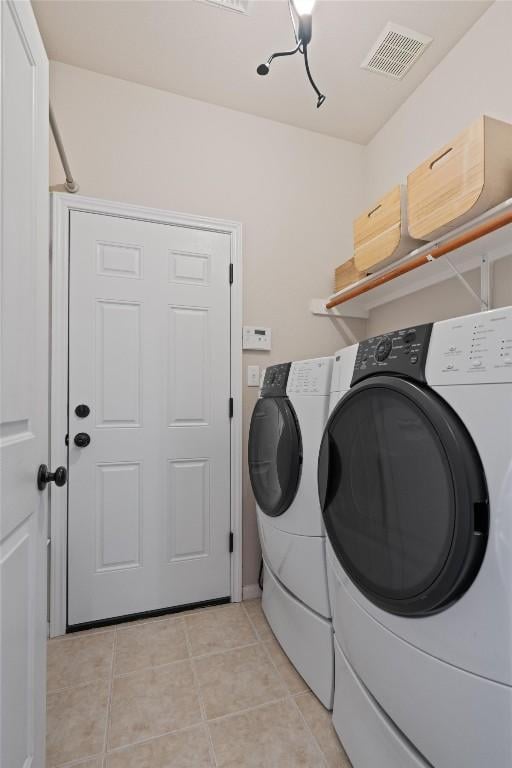 laundry room featuring washing machine and dryer, visible vents, laundry area, and light tile patterned floors