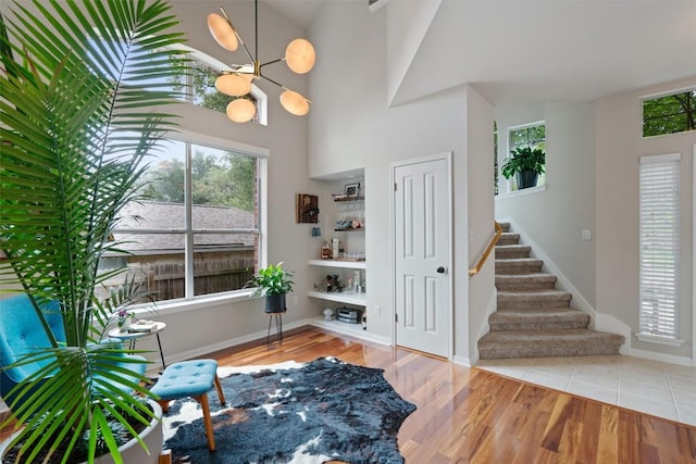 living area featuring baseboards, wood finished floors, a high ceiling, and stairway