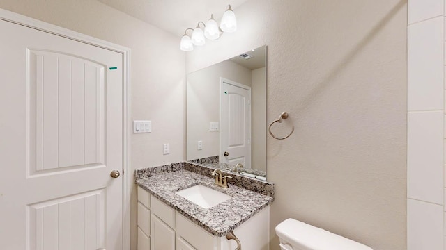 half bath featuring visible vents, vanity, and toilet