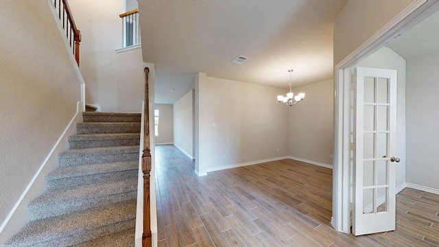 stairway featuring a chandelier, wood finished floors, and visible vents