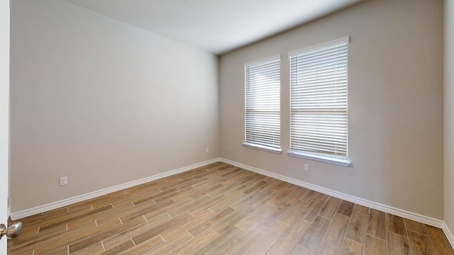 spare room with baseboards and light wood-type flooring