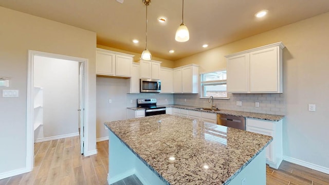kitchen featuring light wood finished floors, stainless steel appliances, a sink, tasteful backsplash, and white cabinetry