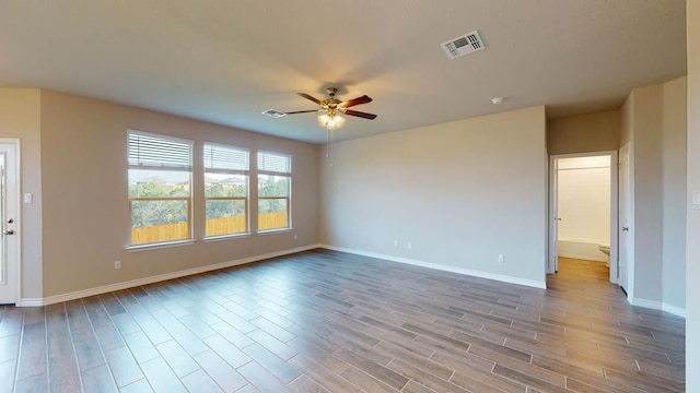 unfurnished room with baseboards, a ceiling fan, wood finished floors, and visible vents