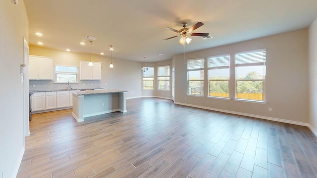 kitchen featuring open floor plan, a wealth of natural light, a ceiling fan, and baseboards