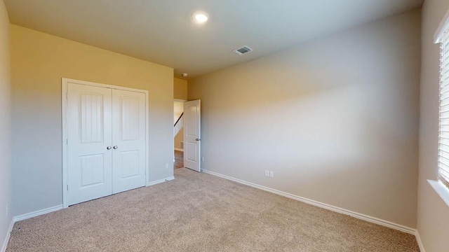 unfurnished bedroom featuring a closet, carpet floors, visible vents, and baseboards