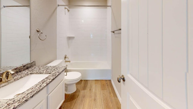 bathroom with wood finished floors, toilet, vanity, and  shower combination