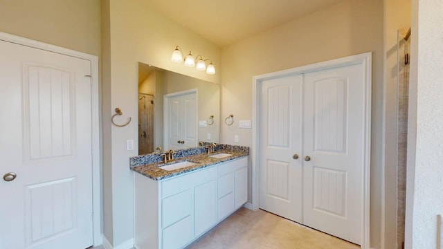 full bathroom with double vanity, tile patterned floors, tiled shower, and a sink