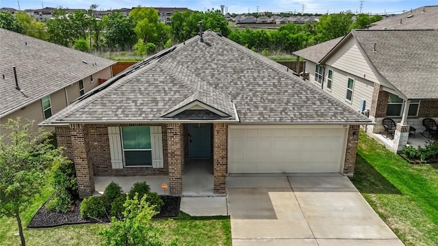 109 Rochester Ln, Hutto, TX 78634 - view of front of house with roof with shingles, brick siding, a garage, concrete driveway, and a residential view