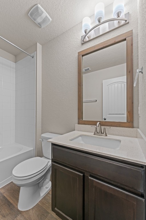 109 Rochester Ln, Hutto, TX 78634 - full bathroom with toilet, vanity, wood finished floors, a textured wall, and tub / shower combination