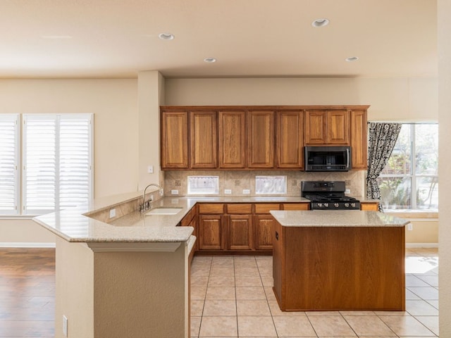 2101 Burnie Bishop Pl, Cedar Park, TX 78613 - kitchen featuring stainless steel appliances, a peninsula, backsplash, brown cabinets, and recessed lighting