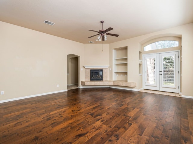 2101 Burnie Bishop Pl, Cedar Park, TX 78613 - unfurnished living room with built in features, ceiling fan, dark wood-style flooring, arched walkways, and a fireplace