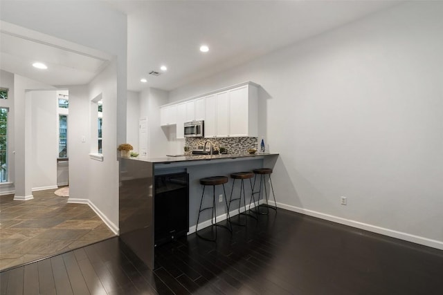 2918 N 620th Rd Unit O282, Austin, TX 78734 - kitchen with stainless steel microwave, white cabinetry, a kitchen breakfast bar, tasteful backsplash, and baseboards