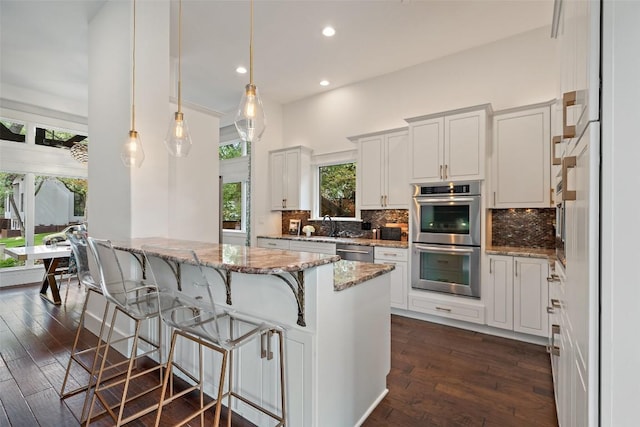 4828 Timberline Dr, Austin, TX 78746 - kitchen featuring appliances with stainless steel finishes, decorative backsplash, light stone countertops, dark wood-type flooring, and recessed lighting