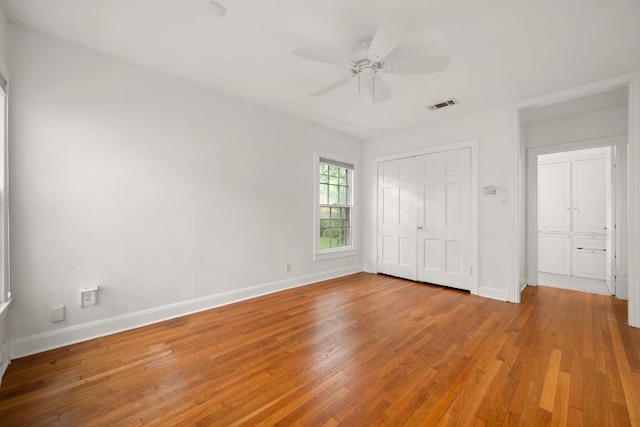unfurnished bedroom with baseboards, visible vents, a ceiling fan, wood finished floors, and a closet