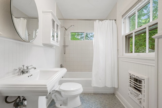 full bath featuring wainscoting, plenty of natural light, heating unit, and shower / bathtub combination with curtain